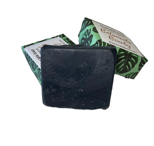 Black, activated charcoal, soap bar with green and white packaging featuring leaf designs on a white background
